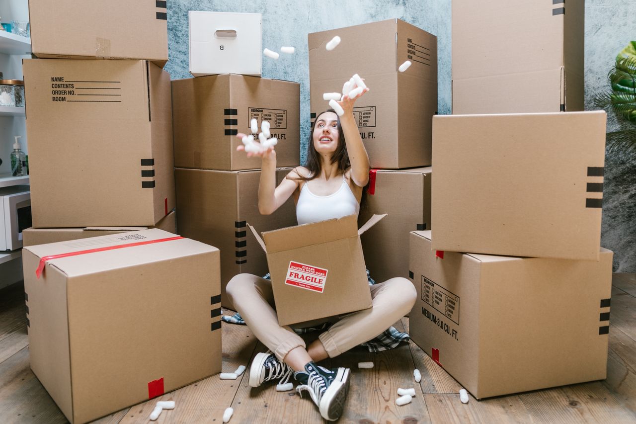 Crafting Captivating Headlines: Your awesome post title goes here Young woman surrounded by cardboard boxes, happily moving into her new apartment.